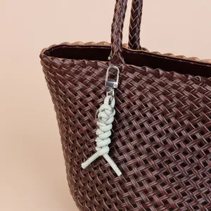 Leather woven bag charm keychain with metal clasp for stylish everyday use and decoration.