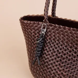 Detailed view of dark brown woven leather tote bag with stylish black rope keychain accessory.