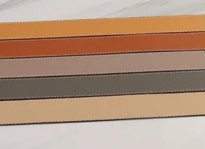 Close-up detail shot of wide leather bag straps in various colors with white stitching.