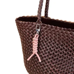 Stylish brown woven leather tote bag with a charming pink braided keychain charm accessory.