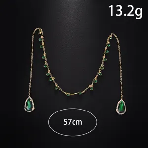 Primo piano dei dettagli della catena facciale verde a goccia con strass luminosi e maglie dorate.