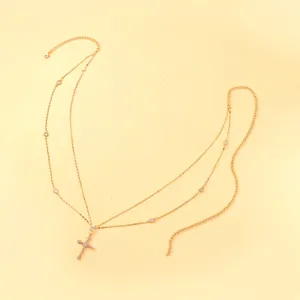 Detail view of the multi-layer gold waist chain with crystal cross pendant and rhinestones.