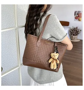 Brown woven leather tote bag with plush bear charm, stylish large capacity shoulder bag for women