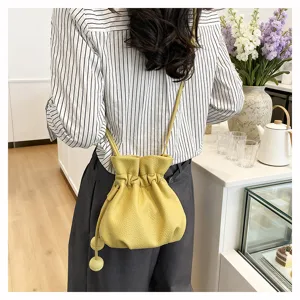 Vue détaillée d'un sac seau en cuir jaune avec cordon de serrage porté à l'épaule, chic.