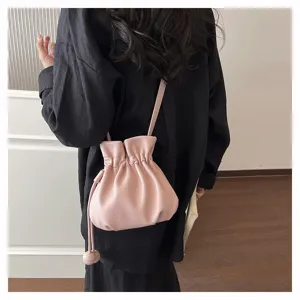 Vue détaillée du sac seau rose en cuir avec cordon, montrant texture douce et bandoulière.