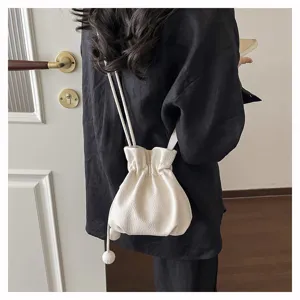 Vue détaillée d'un sac seau à cordon uni chic, design élégant à bandoulière et porté épaule.