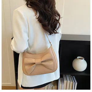Chic Korean style beige crescent shoulder bag with large bow, perfect for daily commuting.