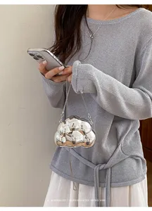 Gros plan d'un mini sac à main métallique argenté en forme de nuage avec une fine bandoulière.