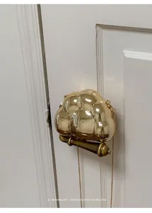 Détail d'un sac à main pochette nuage métallique doré avec une chaîne très élégante.