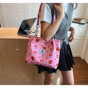 Detail view of a pink tote bag featuring cute strawberry and cherry prints with chain strap.