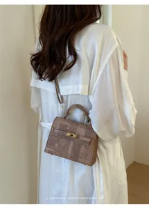Sac à main rétro porté par le mannequin, avec imprimé journal unique et élégante fermeture.