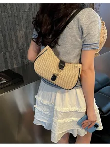 Detailed view of women's straw woven hobo shoulder bag with black leather trim and clasp.