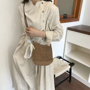 Handmade woven mini crossbody bag for women, stylish knit phone bag with ribbon pendant for daily wear.