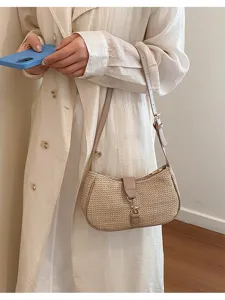 Detail shot of the beige woven underarm hobo bag featuring stylish metal lock and leather strap.