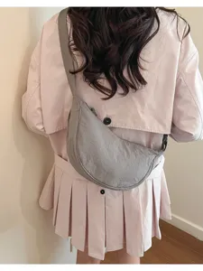 Vista dettagliata di una borsa a tracolla grigia in nylon con giacca rosa casual.