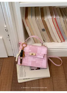 Gros plan élégant du sac à main rose rétro style Kelly avec fermoir tournant doré.