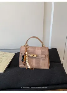 Détail de sac à main rétro à carreaux, serrure dorée élégante et charmant pendentif.