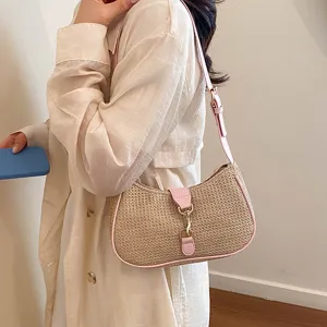 Woven straw hobo shoulder bag for women with pink leather trim and metal piston lock closure.