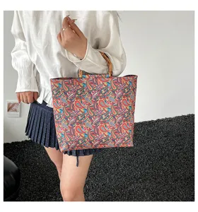 Gros plan detaille du sac cabas paisley colore dote de poignees en bambou elegantes.