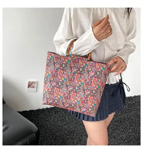 Gros plan detaille d'un sac cabas imprime de motif paisley avec des poignees en bambou.