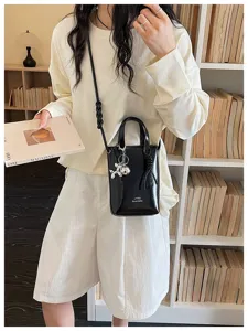 Sac bandoulière noir brillant minimaliste uni élégant avec détail de charme, vue de détail