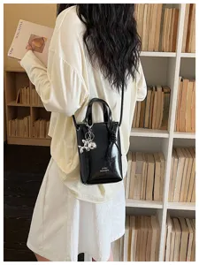 Vue detaillee d'un petit sac bandouliere chic en cuir vernis noir pour femme elegante.