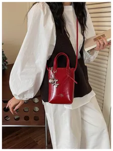 Détail de sac bandoulière vernis rouge, mini sac cabas avec charm chien ballon argent