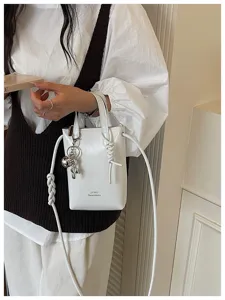 Vue rapprochée d'un sac seau blanc minimaliste avec poignée et bandoulière chic.