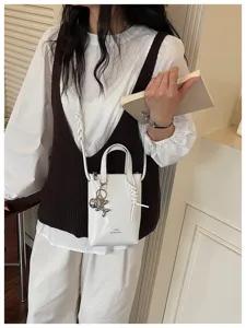 Vue détaillée d'un petit sac bandoulière blanc élégant avec sangle torsadée et pendentif.