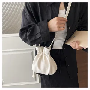 Vue détaillée du sac seau blanc à cordon, élégant sac bandoulière en cuir texturé pour femmes.