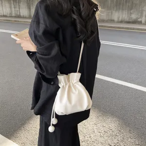 Élégant sac seau blanc avec cordon pour femmes, sac bandoulière minimaliste et chic.