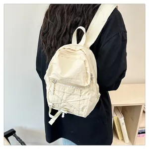 Detail view of lightweight beige mini backpack with front zipper pocket and elastic cord design.