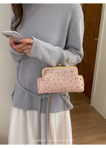 Vue détaillée d'un sac de soirée rose étincelant avec cadre doré et bandoulière.