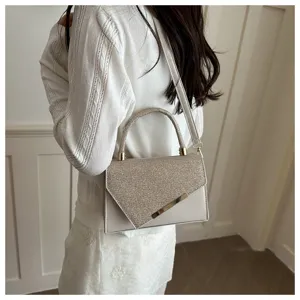 Detail shot of women's fashion glitter flap crossbody handbag with metal hardware and top handle.