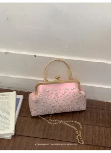Détail de sac de soirée en satin rose avec strass brillants et poignée en métal doré.