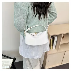 Vue détaillée de l'élégant sac à bandoulière en cuir blanc avec fermoir tournant en métal.
