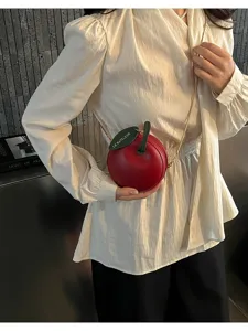 Chic red apple-shaped mini crossbody bag with green leaf accent and gold chain strap.