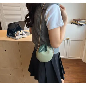 Detailed view of a trendy mini apple-shaped crossbody bag in light green with chic chain strap.