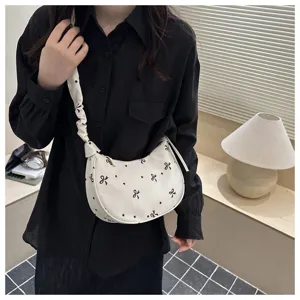 Borsa a tracolla chic in tela bianca con stampe di fiocchi neri e cinturino elegante.