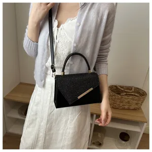 Elegant black evening handbag detail featuring shimmering sequin flap and chic metal bar accent.