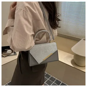 Close-up detail of stylish grey glitter flap crossbody bag with elegant gold hardware.