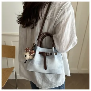 Detail view of fashion casual women bucket bag with blue plaid fabric and cute bear charm pendant.