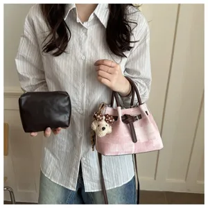 Detailed close-up shot showing the pink plaid handbag texture, cute puppy charm and brown pouch.