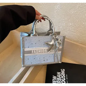 Fashion light blue tote bag with silver trim and star pattern, stylish handbag for women.