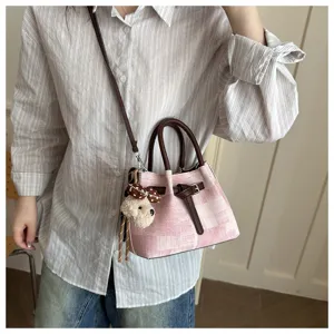 Trendy women's pink plaid bucket bag with brown handles and a cute bear plush pendant for daily commute.