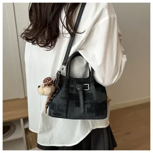 Detail shot of stylish women's bucket bag with cute dog pendant and textured fabric finish.
