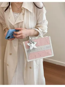 Detailed view of pink star patterned tote handbag with chic handle and star charm.