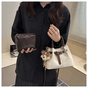 Detail view of stylish women bucket handbag with cute bear pendant and cosmetic pouch accessory.