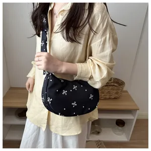 Primo piano dettagliato di una borsa nera a spalla con motivo di fiocchi e pois bianchi.