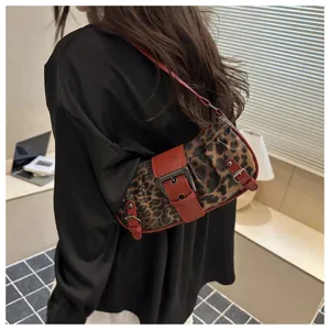 Primer plano de un bolso de hombro con estampado de leopardo y correas rojas y hebillas.
